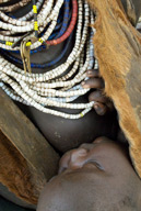 Child held at its mother’s breast, Duss tribal farming community