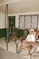 Costa Rica: Guaitíl, old man rocking on porch, with Christmas decorations in background, December