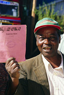 Dairy farmer with book stating amount of milk he has delivered to Nyala.